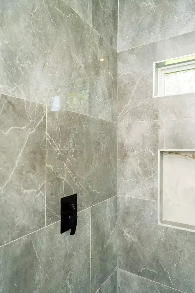 Sleek and sophisticated shower with large format polish stone gray tiles and black accessories that create a bold and modern statement